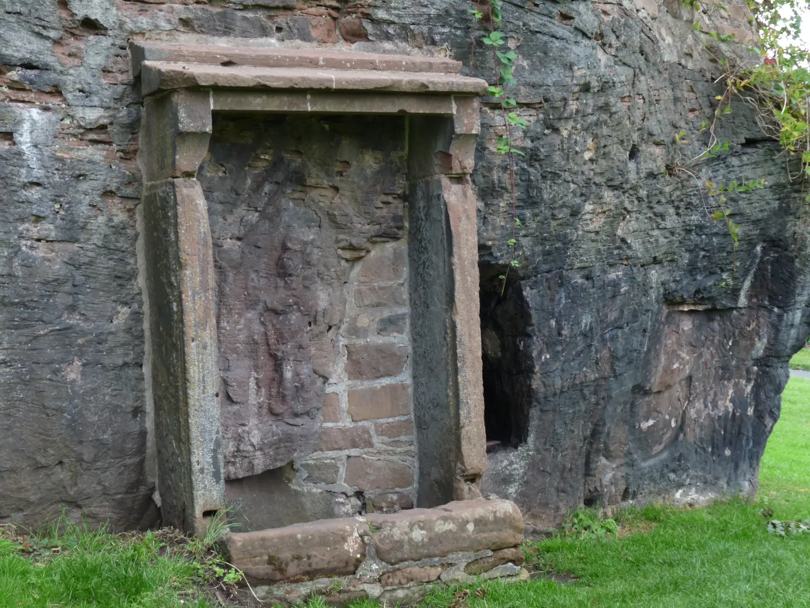 Minerva's Shrine today: a worn carved figure in a stone frame on the face of the sandstone outcrop.