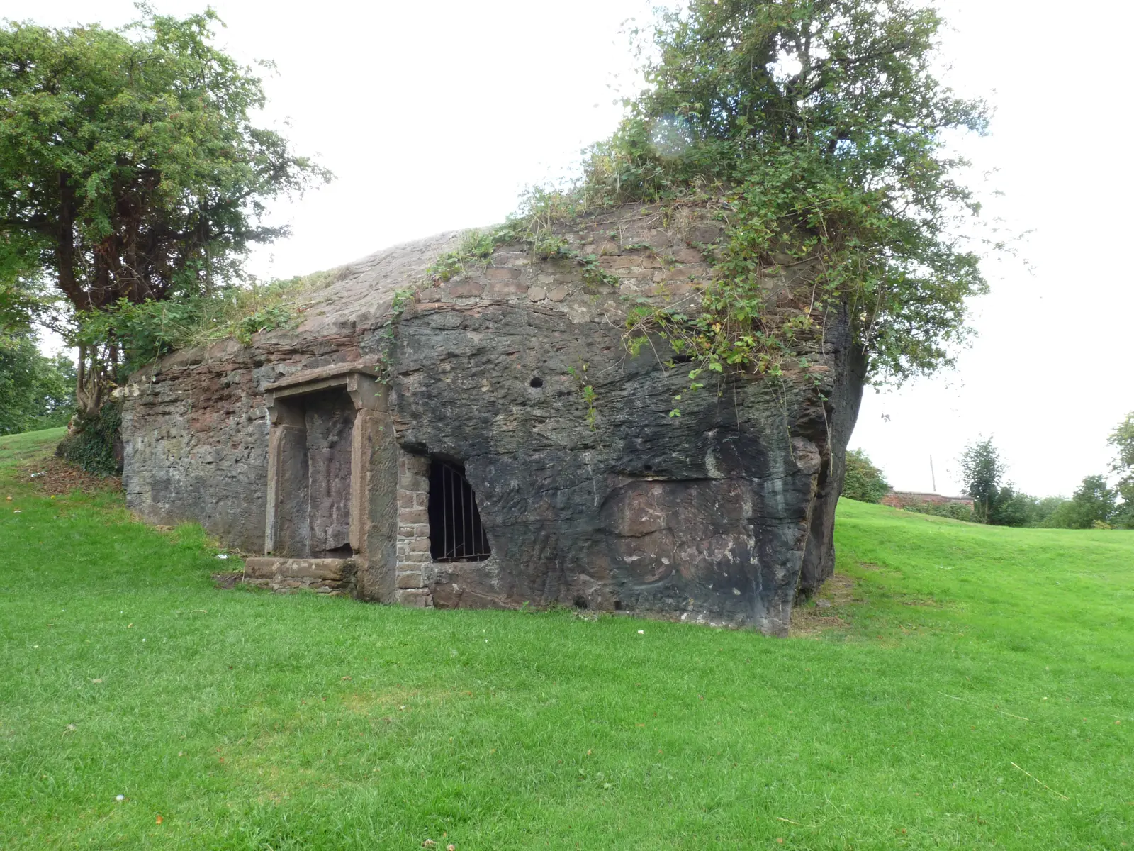Minerva's Shrine in Edgar's Field: a sandstone outcrop on a grassy slope with a small stone-framed niche cut into it.